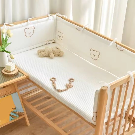 Tour de lit bébé en coton bio beige installé dans un berceau