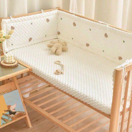 Tour de lit bébé en coton bio beige installé dans un berceau